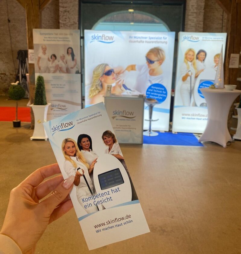 Hochzeitsmesse dauerhafte Haarentfernung Muenchen. Hand hält Flyer von der Hochzeitsmesse.